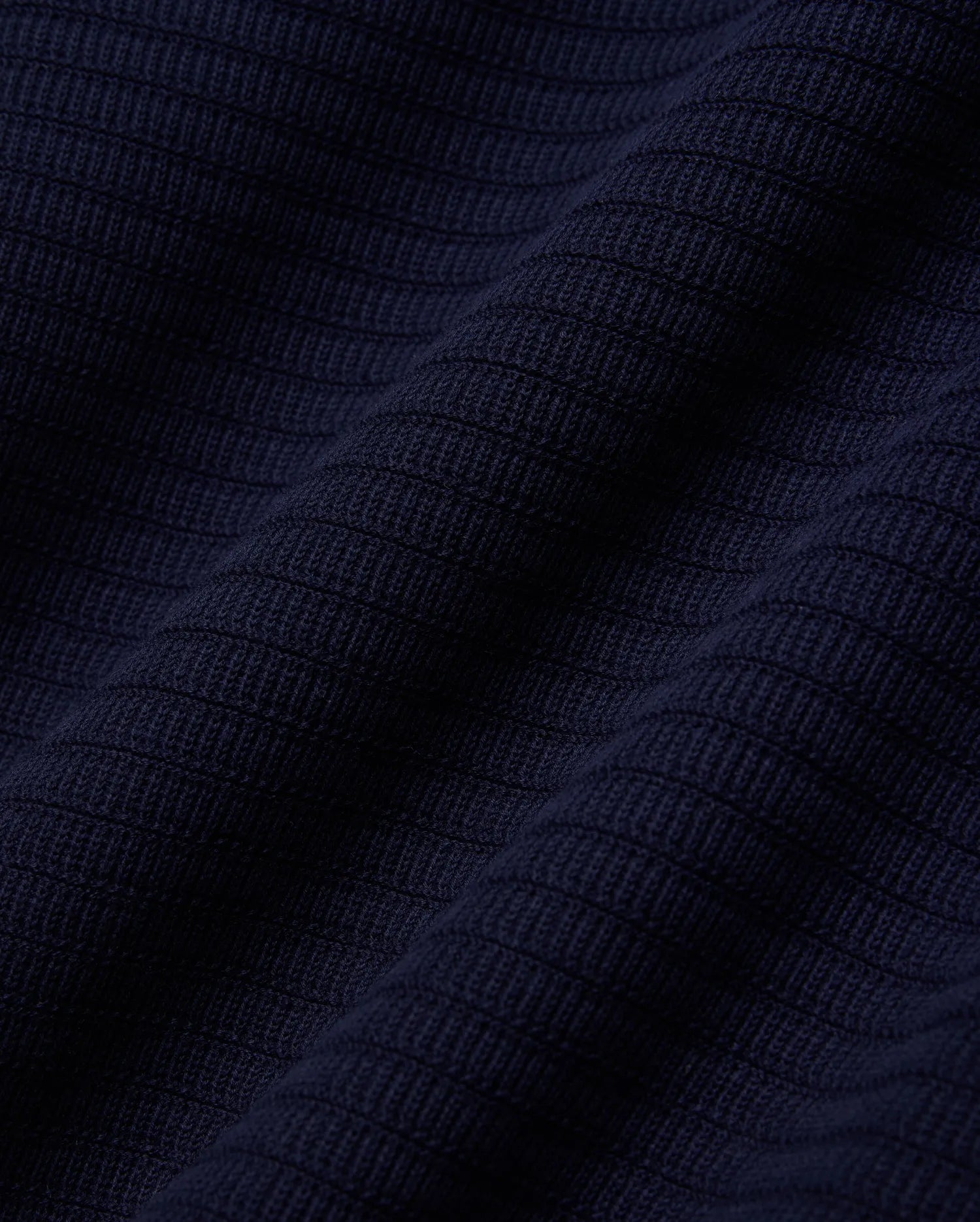 MENS ELOWEN KNIT POLO in deep navy blue, showcasing a finely crafted, horizontally ribbed knit texture with a soft, luxurious feel, characteristic of premium Psycho Bunny apparel.