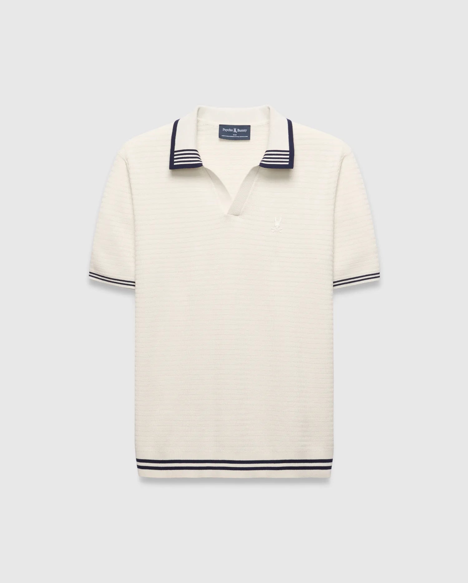 Mens Elowen Knit Polo, cream ribbed knit with navy striped V-neck collar, cuffs, and hem, featuring a small embroidered Psycho Bunny skull logo on the left chest.