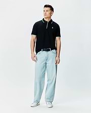 Mens Faye Pique Polo, black classic fit with green and white tipped collar and cuffs, featuring a small embroidered Psycho Bunny skull logo on the left chest.