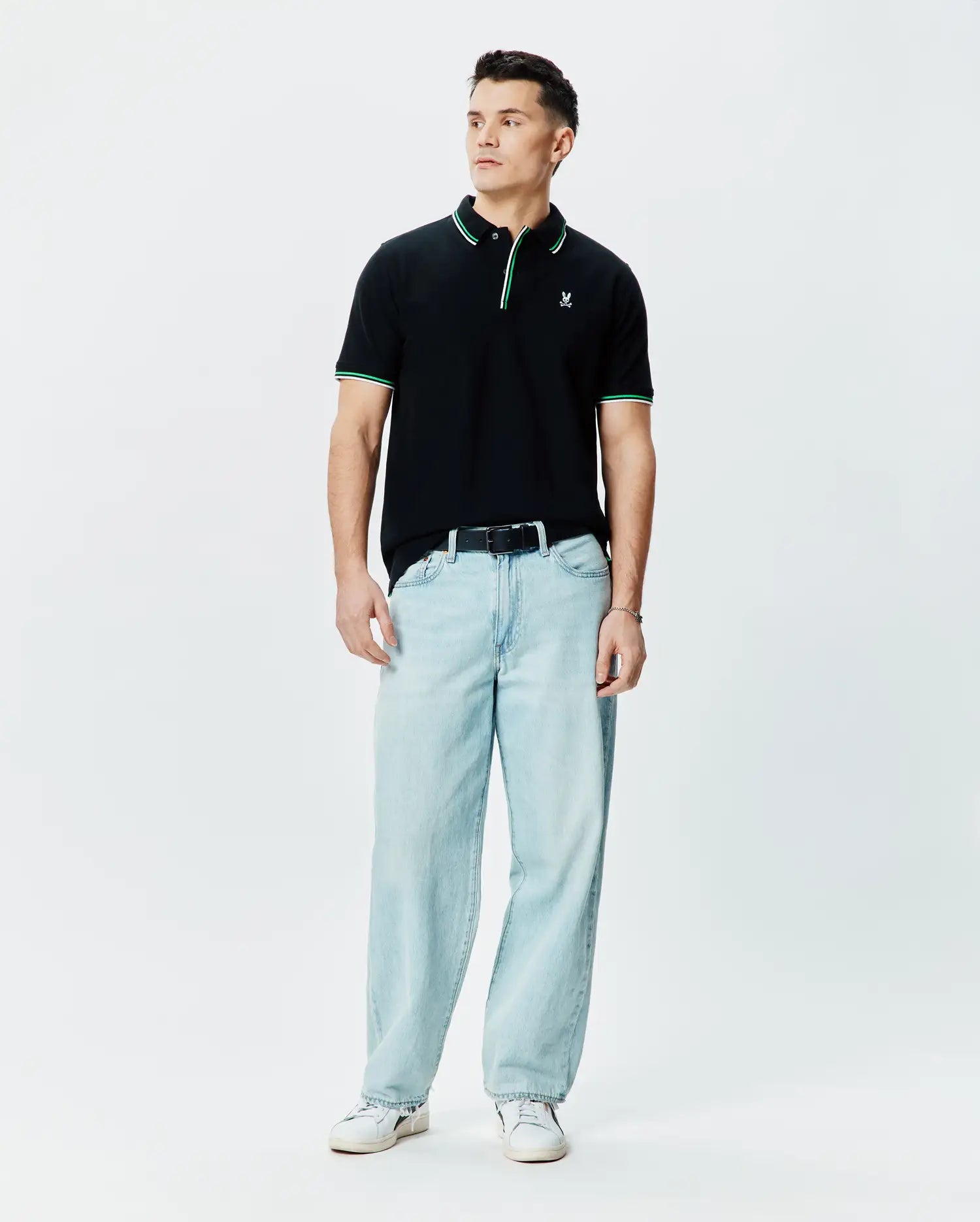 Mens Faye Pique Polo, black classic fit with green and white tipped collar and cuffs, featuring a small embroidered Psycho Bunny skull logo on the left chest.