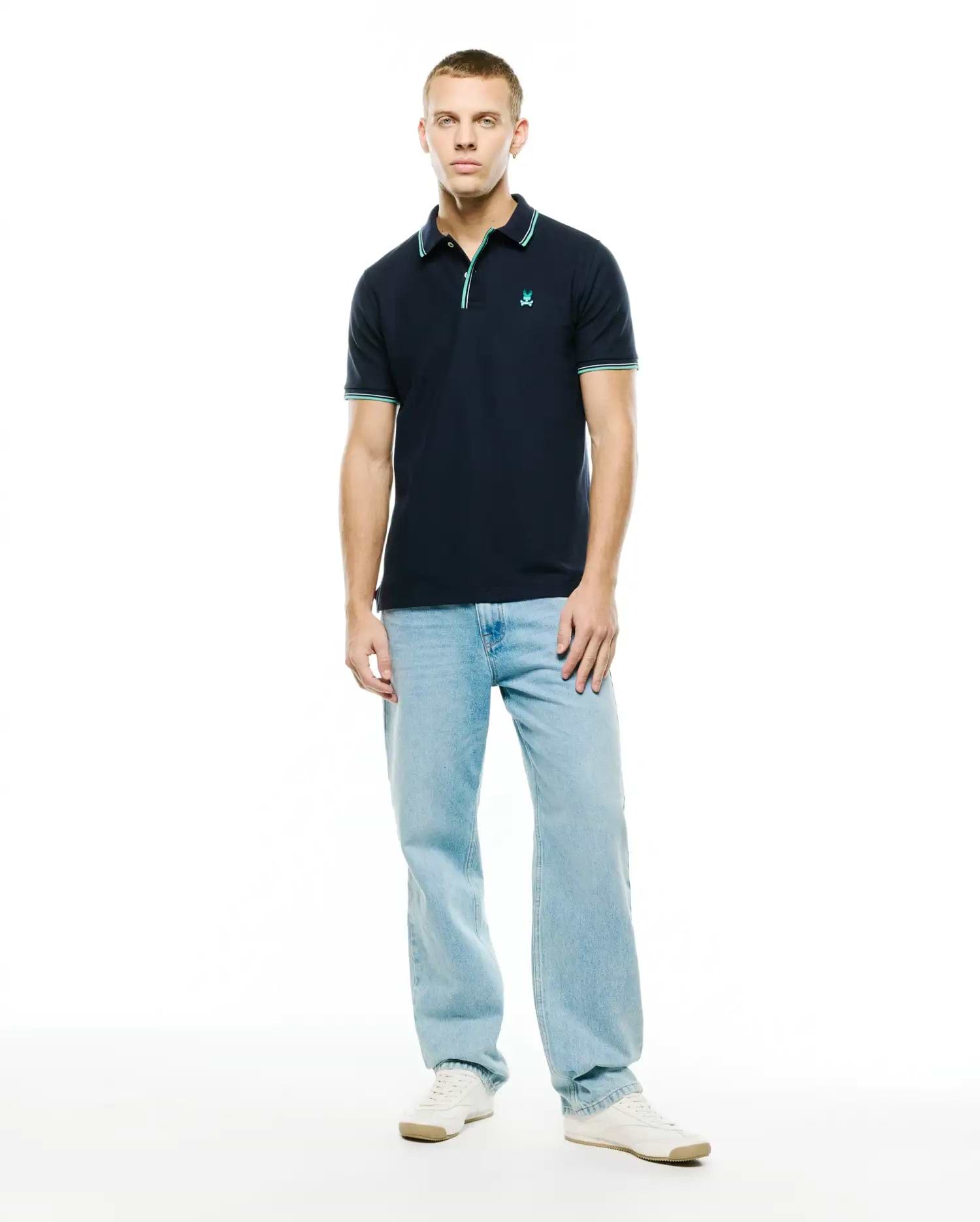 Men's Slade Pique Polo, classic fit navy pique polo shirt with a small embroidered teal Psycho Bunny skull logo on the left chest, featuring ribbed collar and cuffs with teal and white double stripe accents. (4)