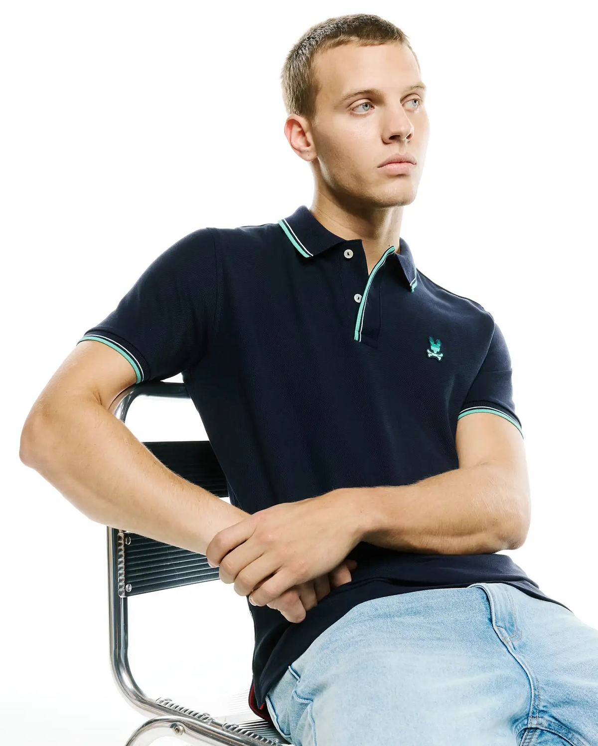 Men's Slade Pique Polo, navy classic fit pique polo with mint green and white tipped collar and cuffs, featuring a small embroidered Psycho Bunny skull logo on the left chest. (1)