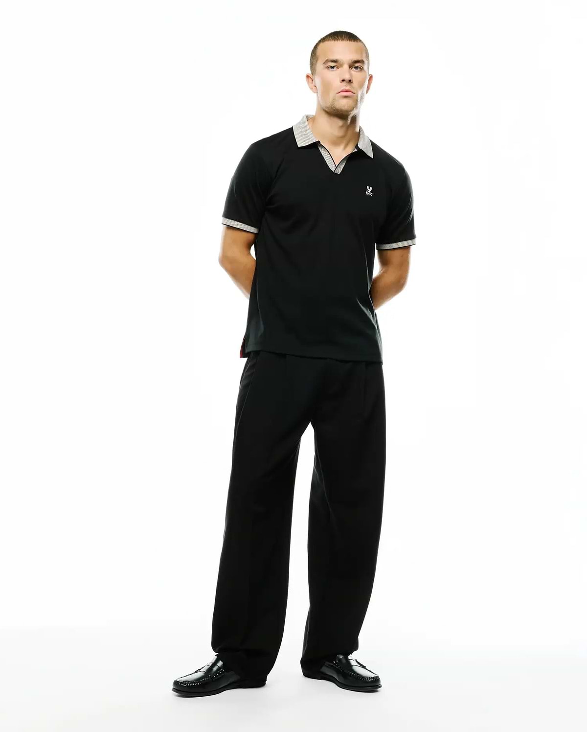 Black Men's Teddy Johnny Collar Polo, classic fit, smooth jersey knit, with grey and white check collar and cuffs, red side slit detail, small white embroidered Psycho Bunny skull logo on left chest. (4)
