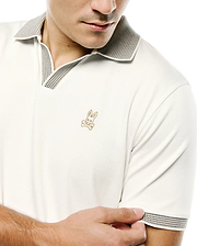 Men's Teddy Johnny Collar Polo in cream, featuring a smooth jersey knit, black and white patterned Johnny collar and sleeve cuffs, with a small gold embroidered Psycho Bunny skull logo on the left chest. (2)