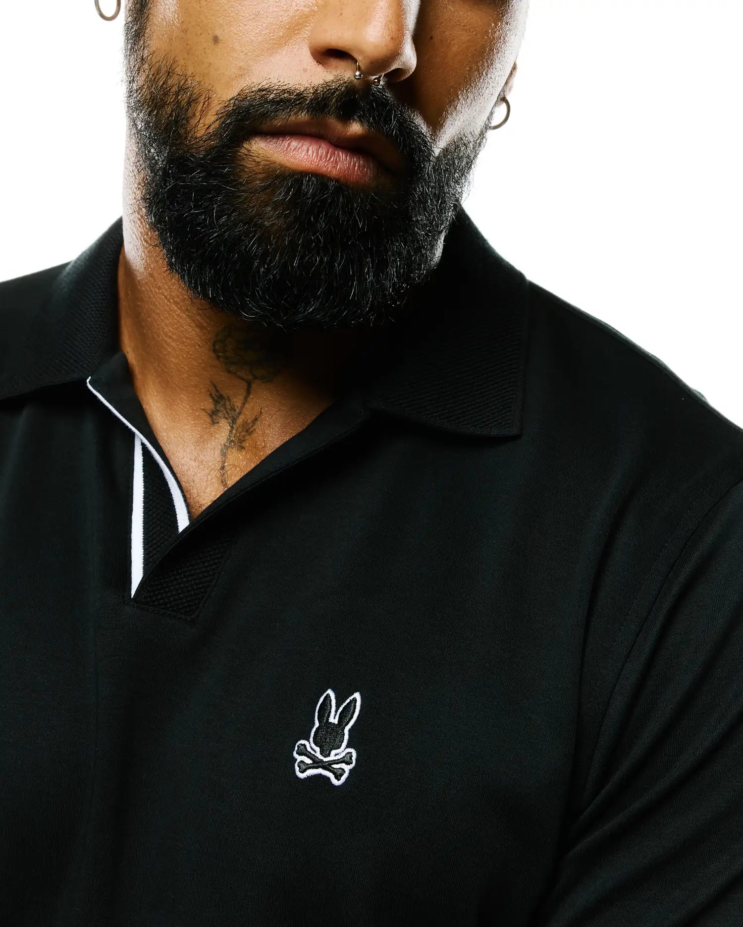 Black Nasser Pima Johnny Polo with a classic fit, featuring a smooth Pima cotton body, pique Johnny collar with white trim, and a small embroidered white Psycho Bunny skull logo on the left chest.
