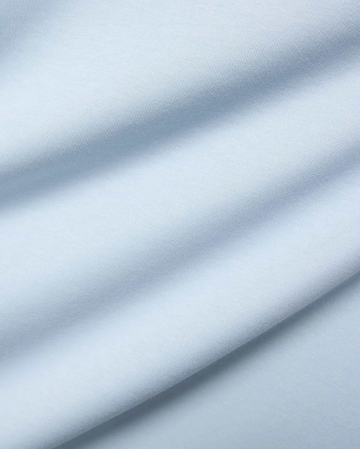 Mens Nasser Interlock Johnny Collar Polo, featuring a close-up of its soft, light blue interlock knit fabric with subtle texture and elegant draped folds.