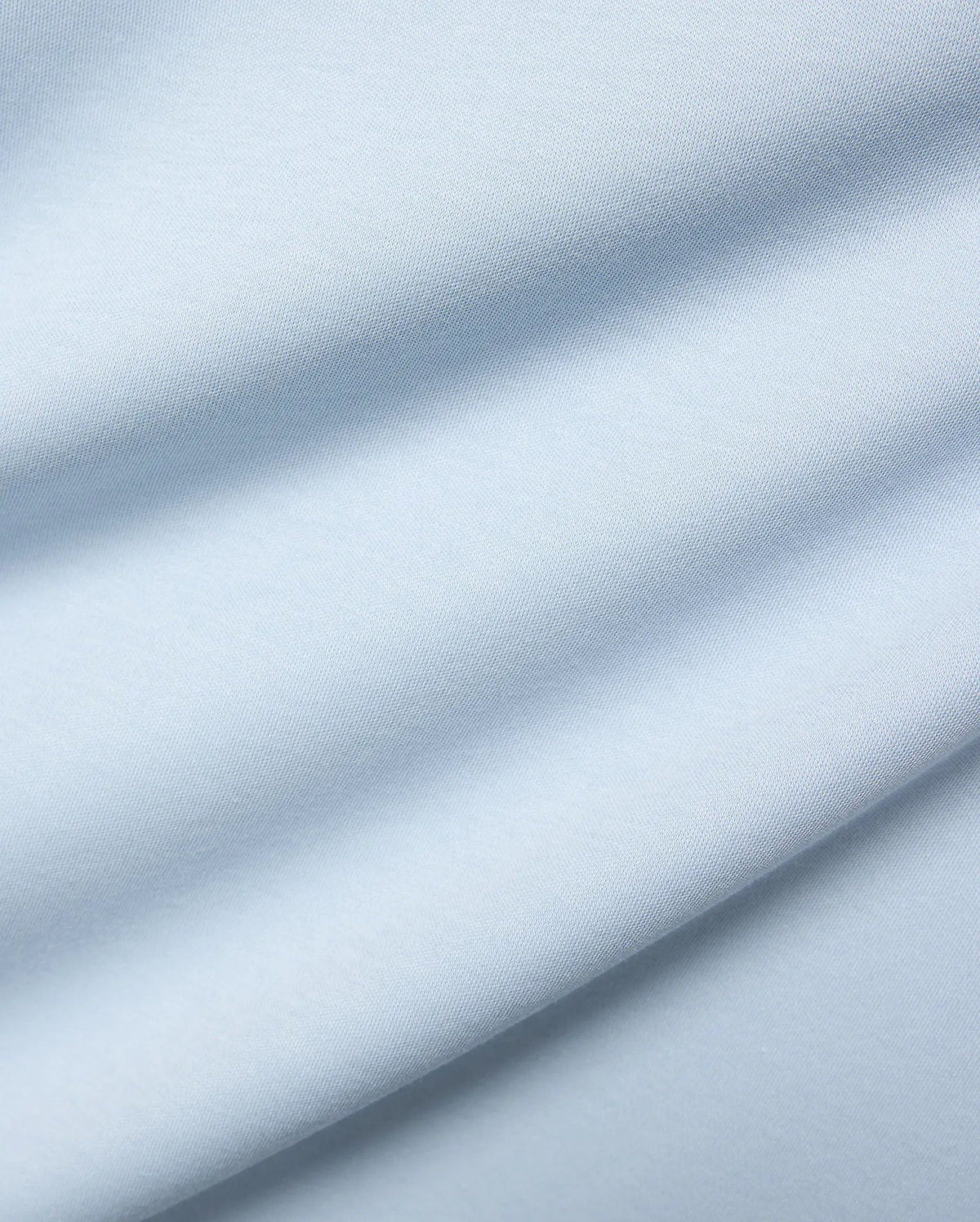 Mens Nasser Interlock Johnny Collar Polo, featuring a close-up of its soft, light blue interlock knit fabric with subtle texture and elegant draped folds.
