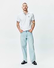 Mens Nasser Polo, a classic fit white pique polo with black tipping on the collar and sleeve cuffs, featuring a small embroidered Psycho Bunny skull logo on the left chest.