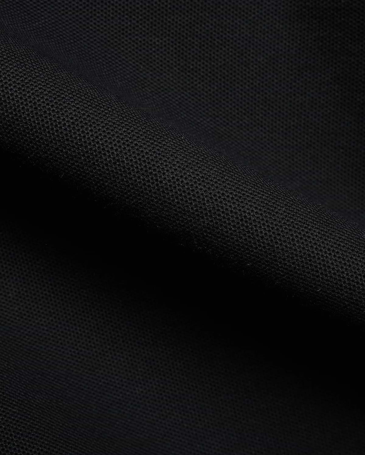 Detailed close-up of a rich black pique fabric, revealing the distinctive textured weave of the premium Men's Klaus Pique Polo, a signature Psycho Bunny menswear piece. (6)