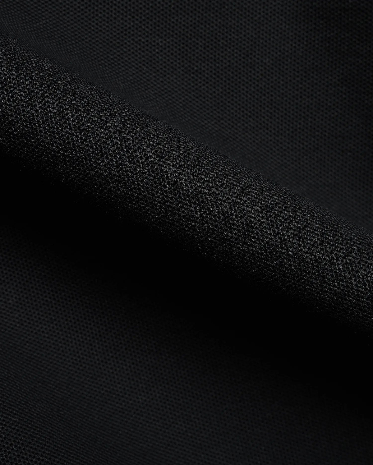 Detailed close-up of a rich black pique fabric, revealing the distinctive textured weave of the premium Men's Klaus Pique Polo, a signature Psycho Bunny menswear piece. (6)