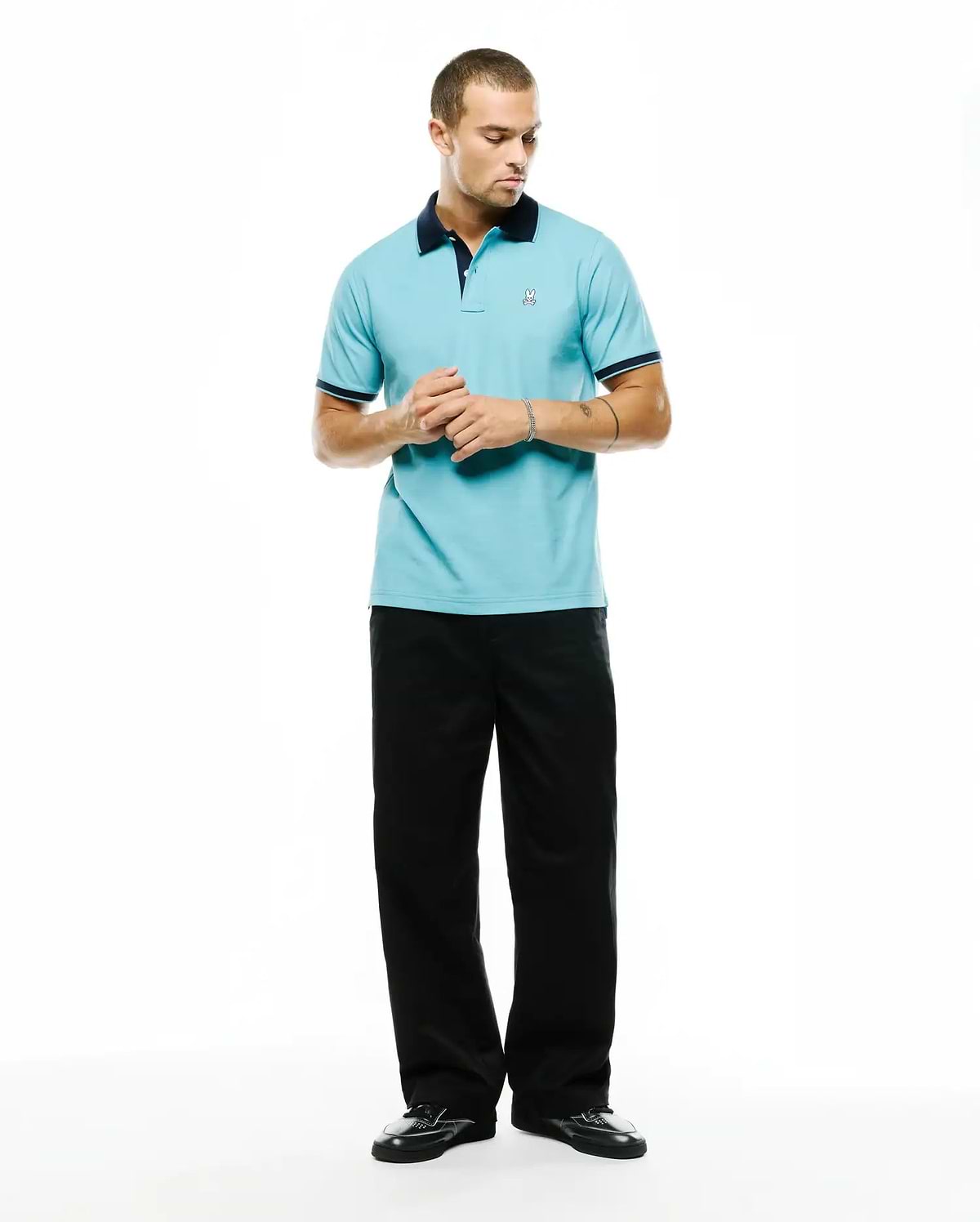 Men's Klaus Pique Polo in light blue, featuring a navy collar and cuffs with white trim. Small embroidered Psycho Bunny skull logo on the left chest. Classic fit. (4)