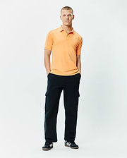 Mens Rhys Sport Polo, a classic fit peach pique polo with white piping on shoulders and collar, featuring a small embroidered Psycho Bunny skull logo on the left chest.
