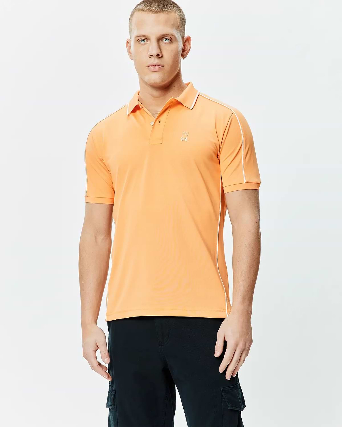 Mens Rhys Sport Polo, vibrant orange smooth performance jersey with white piping on shoulders and sides, classic fit, and small embroidered Psycho Bunny skull logo on left chest.