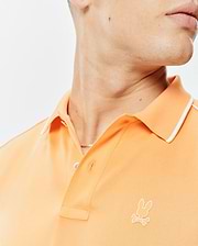 Mens Rhys Sport Polo in peach pique knit, featuring a classic fit, white tipped collar, two-button placket, and a small embroidered white Psycho Bunny skull logo on the left chest.