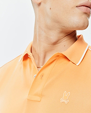 Mens Rhys Sport Polo in peach pique knit, featuring a classic fit, white tipped collar, two-button placket, and a small embroidered white Psycho Bunny skull logo on the left chest.