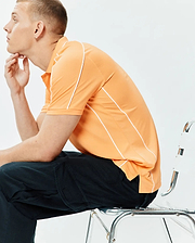 Mens Rhys Sport Polo in vibrant peach pique knit, featuring a classic fit, two-button placket, and distinctive white piping along the shoulders and sides, with side vents.