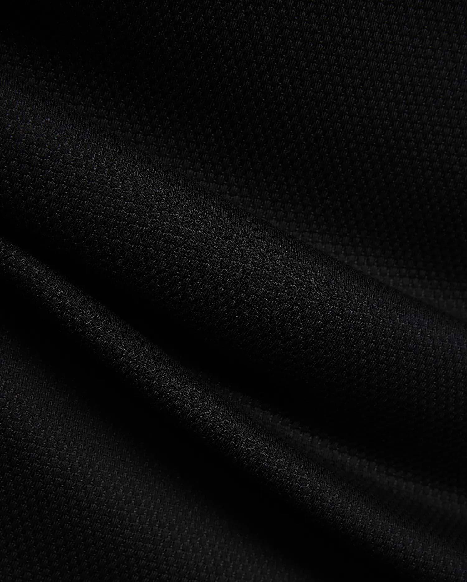 MENS TIERNAN PIQUE POLO in deep black, showcasing its premium, classic textured pique knit fabric with elegant folds, reflecting Psycho Bunny's refined streetwear aesthetic.