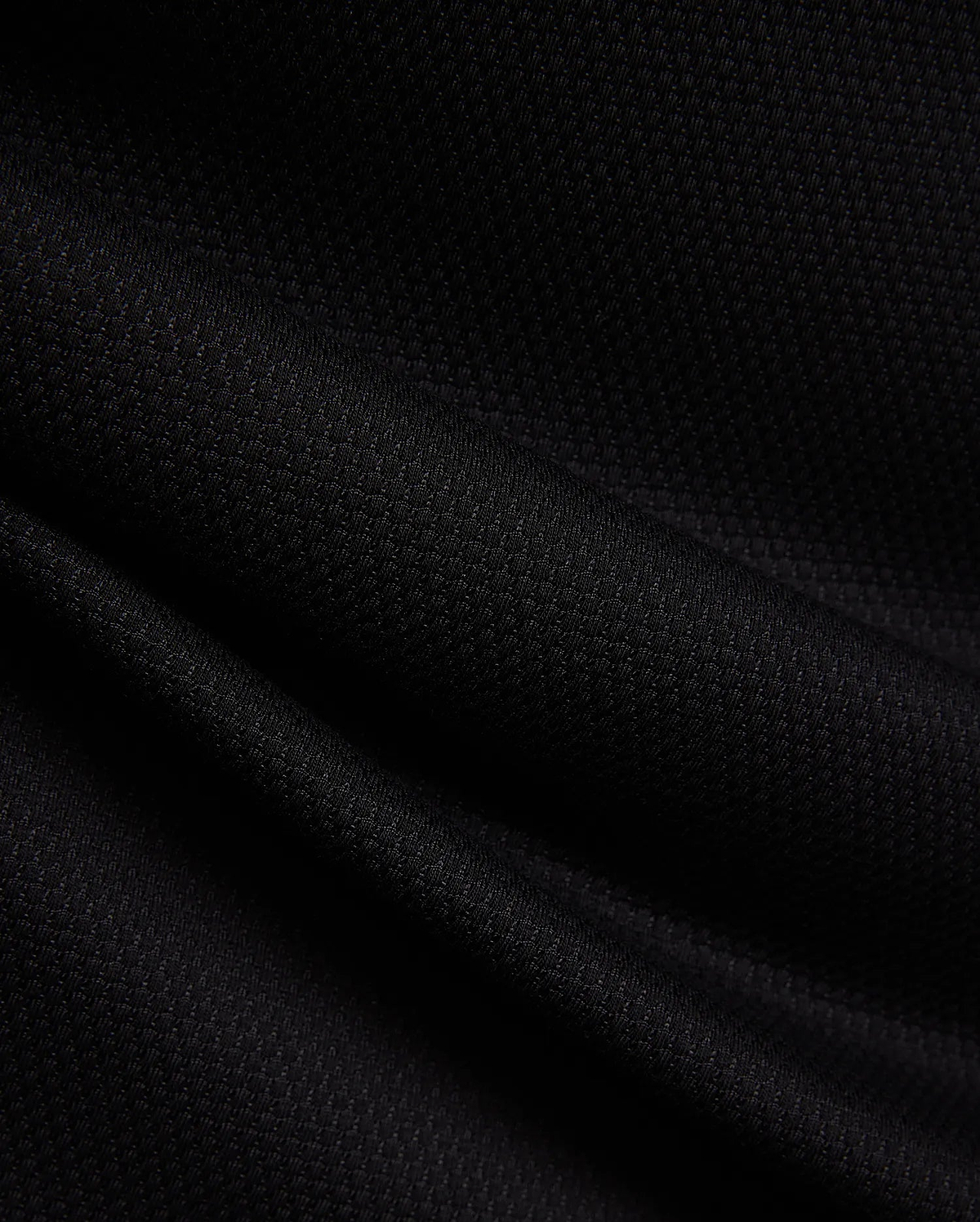 MENS TIERNAN PIQUE POLO in deep black, showcasing its premium, classic textured pique knit fabric with elegant folds, reflecting Psycho Bunny's refined streetwear aesthetic.