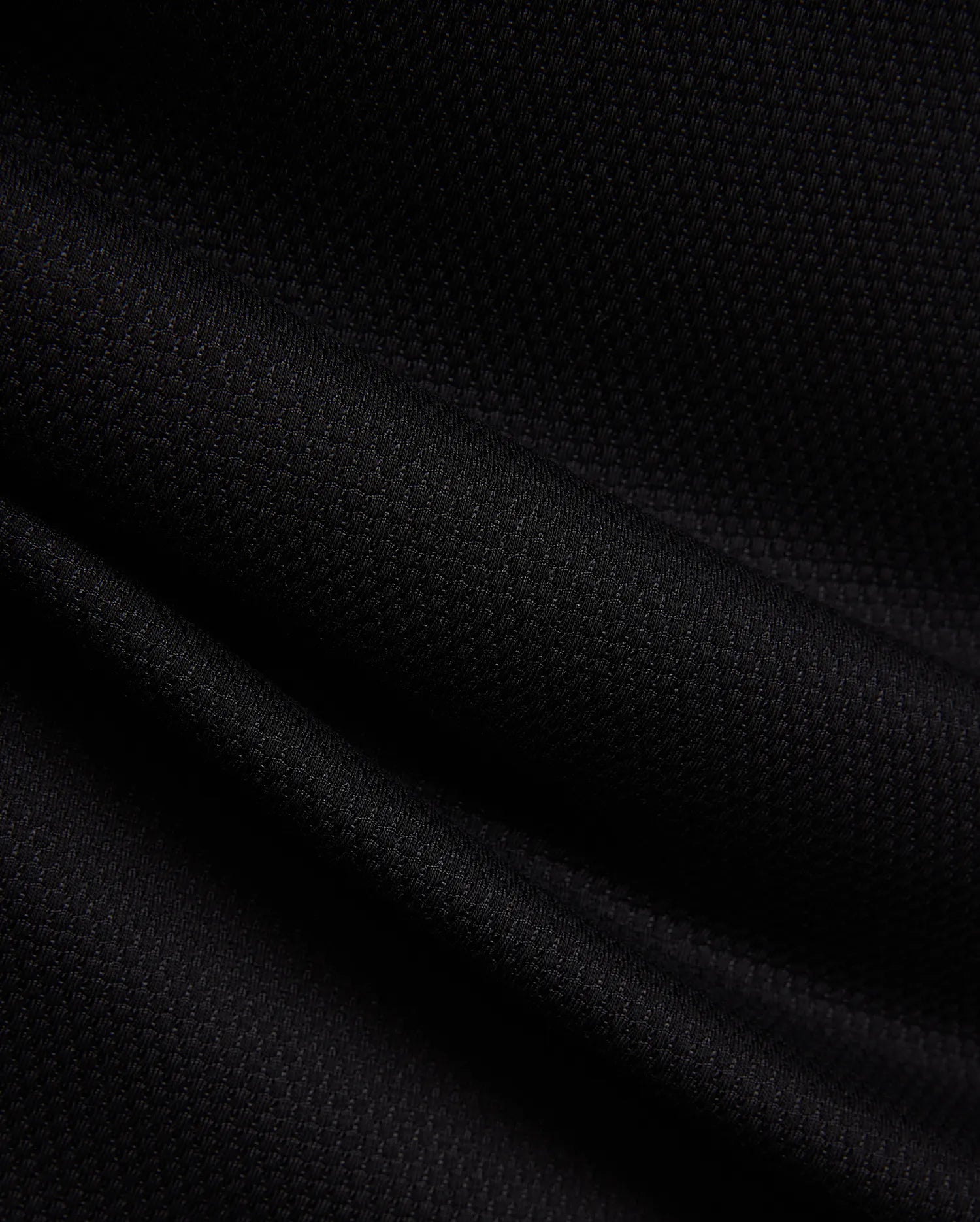 MENS TIERNAN PIQUE POLO in deep black, showcasing its premium, classic textured pique knit fabric with elegant folds, reflecting Psycho Bunny's refined streetwear aesthetic.