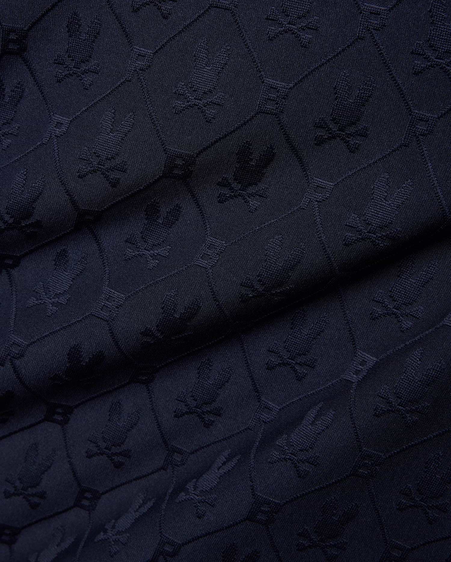 Mens Garry Jacquard Johnny Collar Polo in dark navy, featuring an all-over tone-on-tone jacquard knit pattern of the iconic Psycho Bunny skull logo within hexagonal shapes. (7)