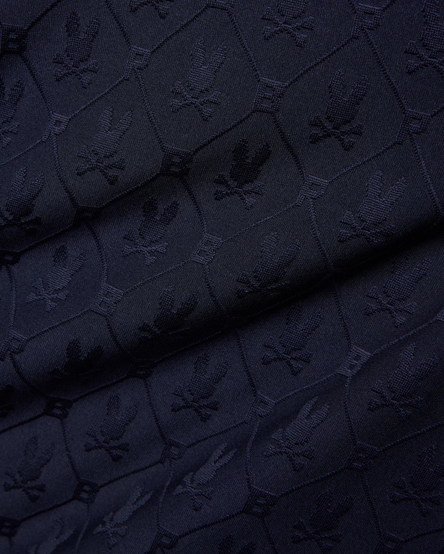 Mens Garry Jacquard Johnny Collar Polo in dark navy, featuring an all-over tone-on-tone jacquard knit pattern of the iconic Psycho Bunny skull logo within hexagonal shapes. (7)