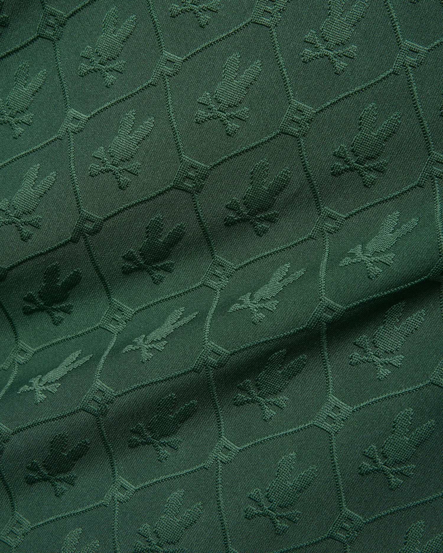 Mens Garry Jacquard Johnny Collar Polo in deep green, featuring an all-over tonal jacquard pattern of the iconic Psycho Bunny skull logo within a hexagonal grid. (9)