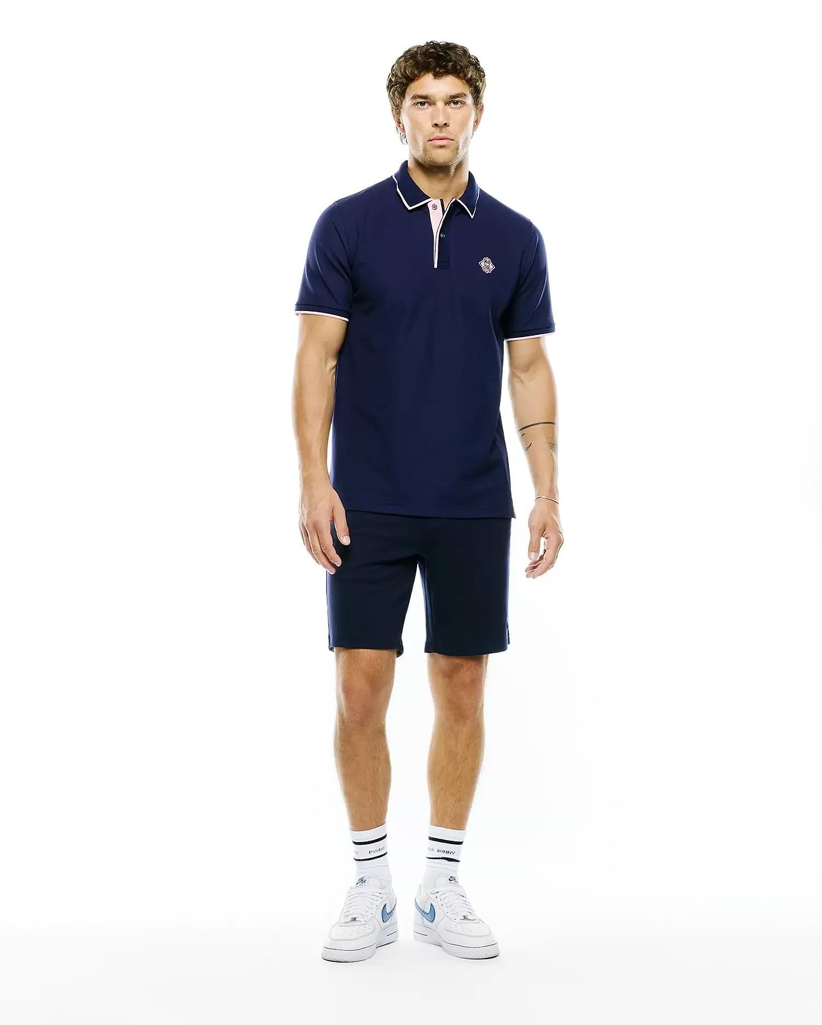 MENS ROBIN PIQUE POLO in navy, classic fit, with white collar tipping, pink placket and cuff trim, and a small embroidered Psycho Bunny skull logo on the left chest.