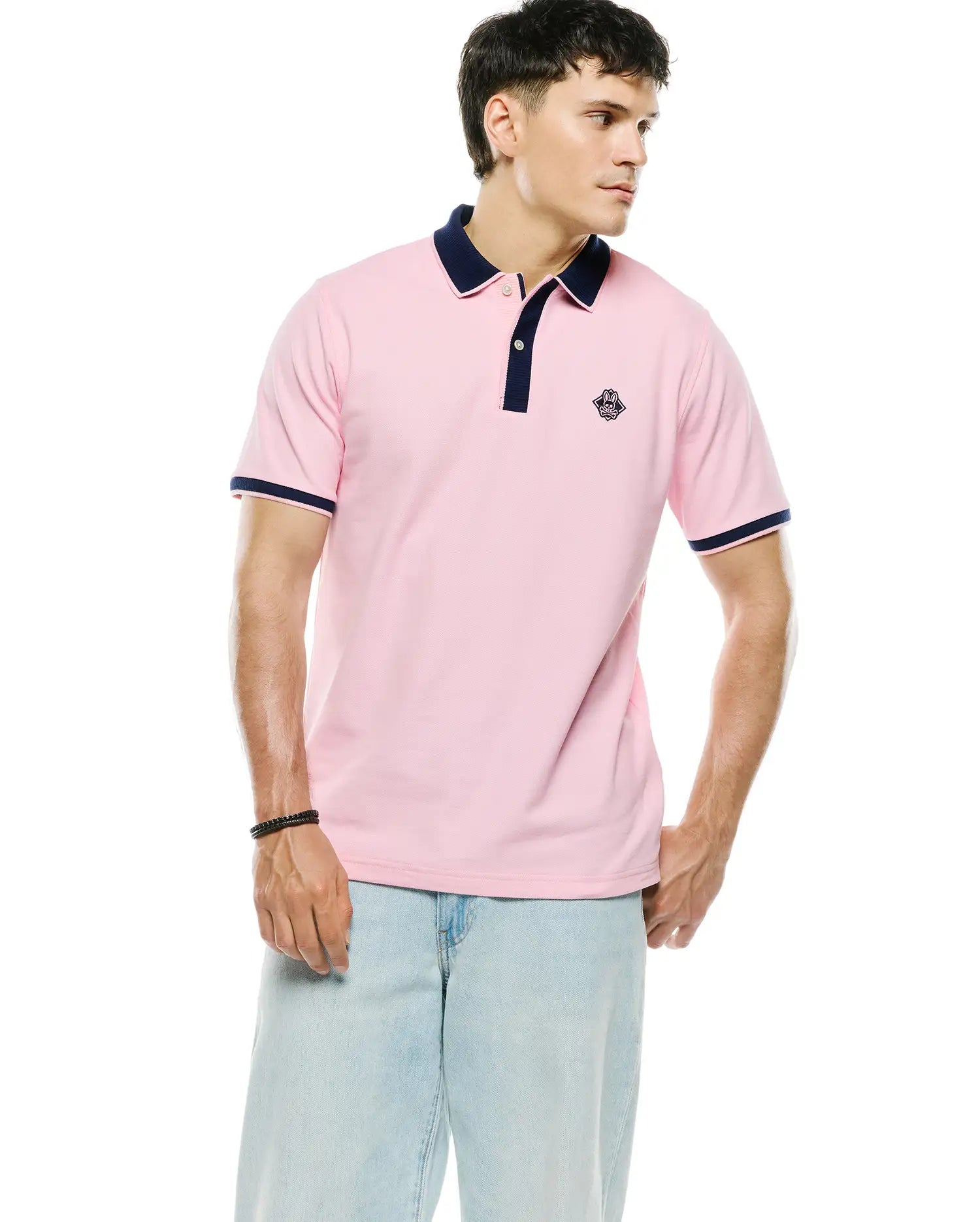 Mens Robin Pique Polo in classic fit pink pique with navy blue collar, placket, and sleeve cuffs, featuring a small embroidered Psycho Bunny skull logo on the left chest.