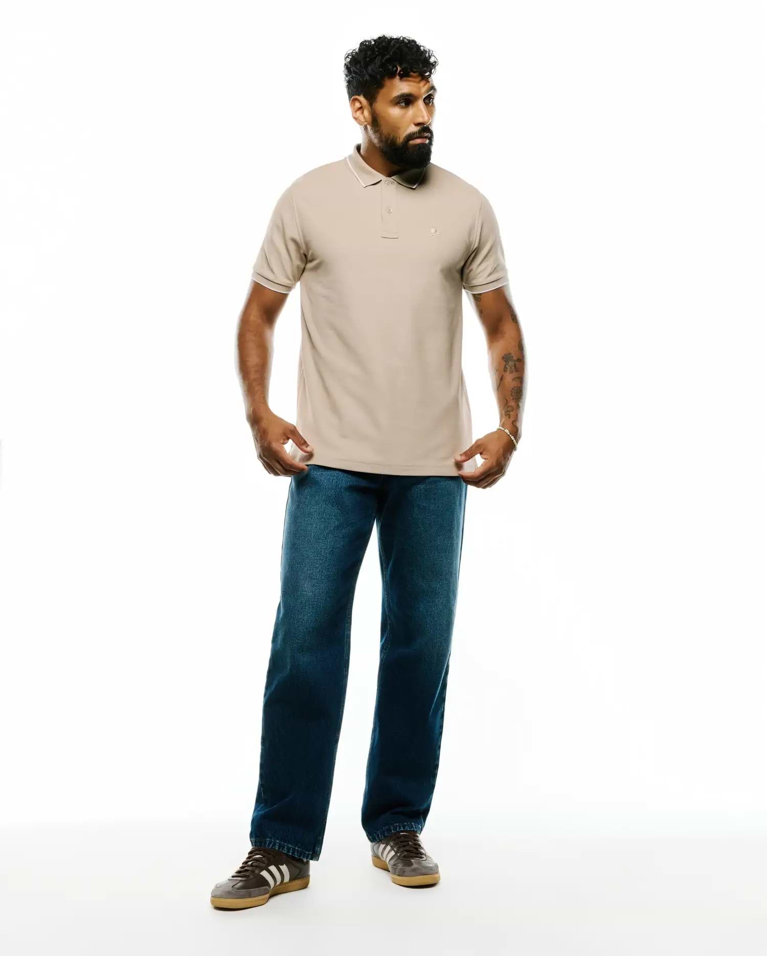 Mens Ringston Pique Polo in classic fit, light beige pique fabric with white tipping on the ribbed collar and cuffs, featuring a small embroidered Psycho Bunny skull logo on the left chest.