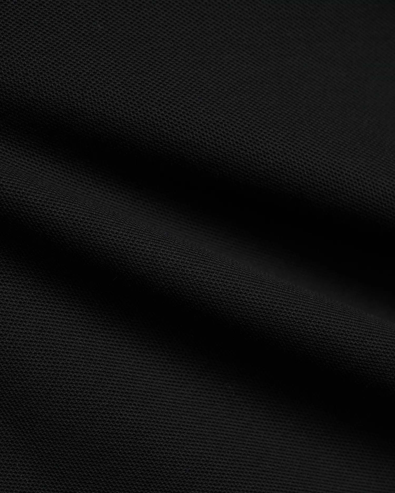 Psycho Bunny Mens Atley Pique Polo in deep black, showcasing the premium, breathable textured pique fabric with subtle folds, perfect for sophisticated streetwear. (6)
