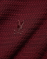 Men's Devon Braided Knit Polo in deep burgundy, featuring a rich braided knit texture and a small, tonal embroidered Psycho Bunny skull logo on the chest. (6)