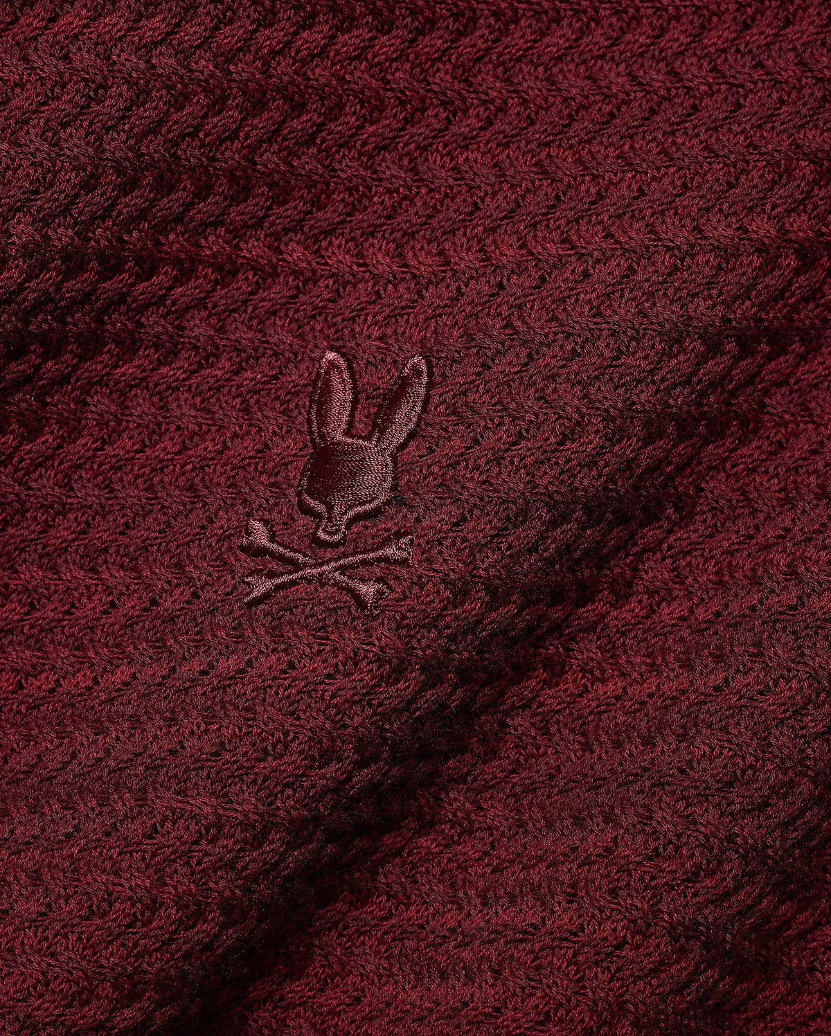 Men's Devon Braided Knit Polo in deep burgundy, featuring a rich braided knit texture and a small, tonal embroidered Psycho Bunny skull logo on the chest. (6)