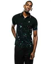 Mens Malcolm Splatter Polo. Black classic fit pique polo with vibrant pink, blue, white paint splatter print, white double-stripe collar/cuff tipping, and a small white embroidered Psycho Bunny skull logo. (3)