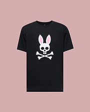 The Psycho Bunny MENS ARCHIVE BUNNY GRAPHIC TEE (MT0200031) is a black 100% Pima cotton shirt made in Peru, featuring a bold white skull with rabbit ears and pink inner accents, displayed against a light mauve background.