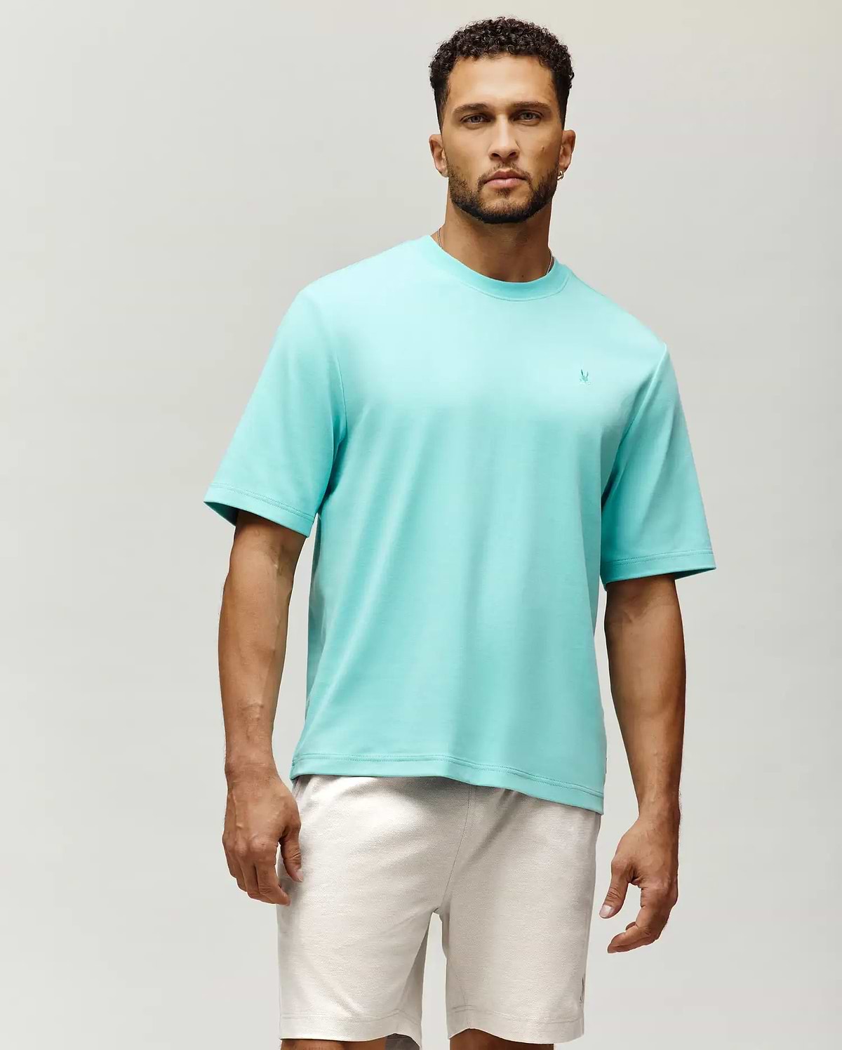 Mens Adam Interlock Tee, a vibrant aqua, relaxed fit, smooth interlock knit t-shirt featuring a small, embroidered Psycho Bunny skull logo on the left chest.