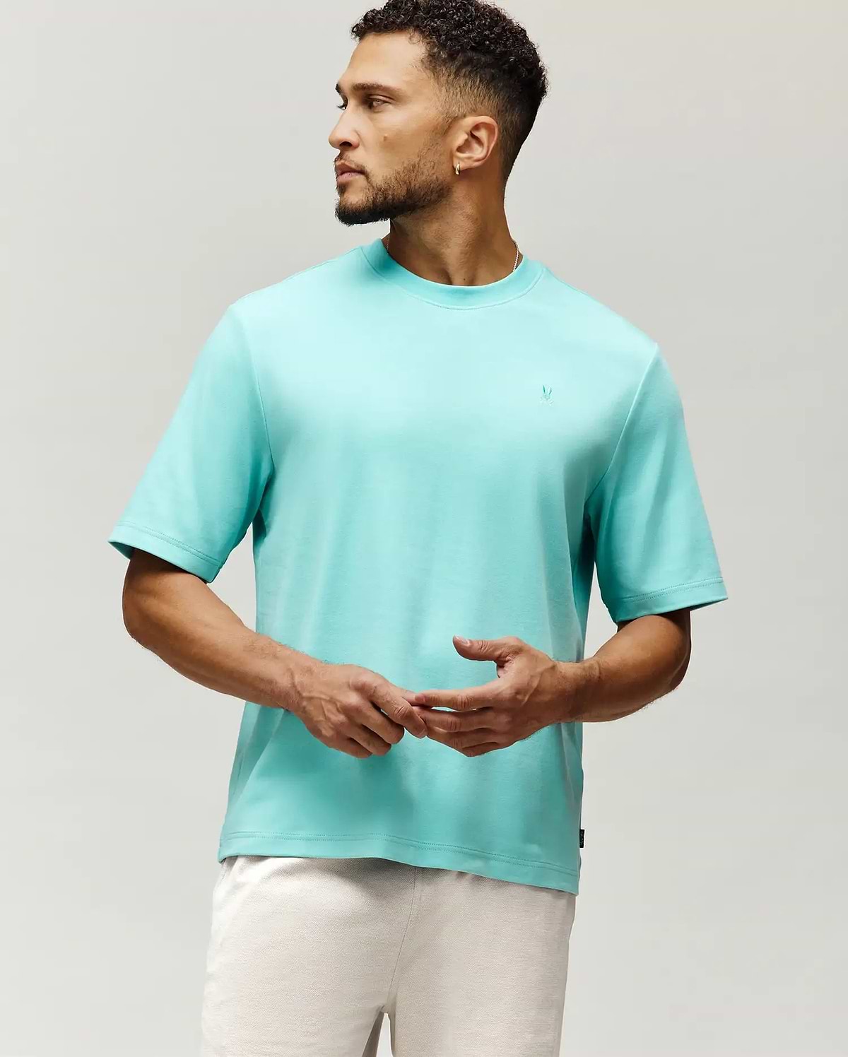 Mens Adam Interlock Tee in vibrant aqua, featuring a relaxed fit, smooth interlock knit, and a small tonal embroidered Psycho Bunny skull logo on the left chest.