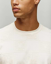 Mens Gio Tee in cream, featuring a classic fit and soft jersey fabric with an all-over embossed checkerboard pattern of the Psycho Bunny skull logo and brand name.