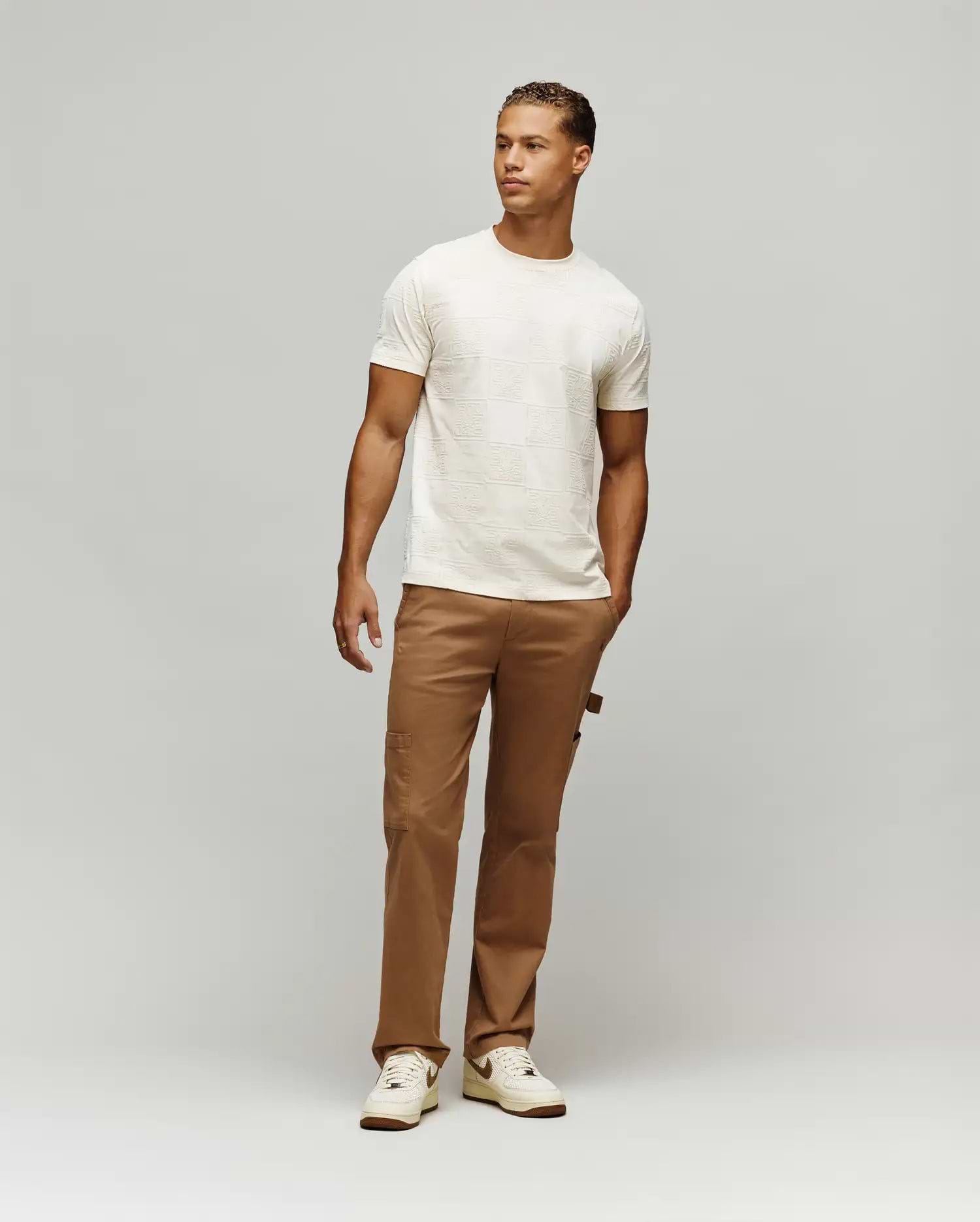 Mens Gio Tee cream textured jersey t-shirt with an all-over embossed checkerboard pattern featuring the iconic Psycho Bunny skull logo, designed for a comfortable classic fit.