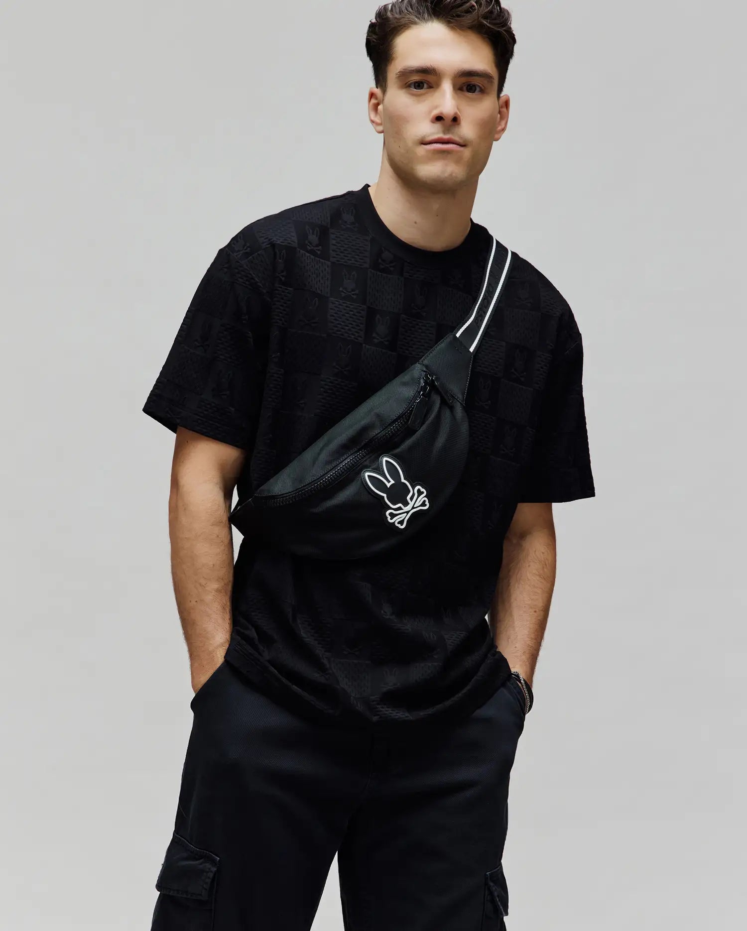 Mens Dustin Oversized Tee, a black oversized t-shirt with an all-over embossed checkerboard pattern featuring the Psycho Bunny skull logo, crafted from textured jersey fabric.