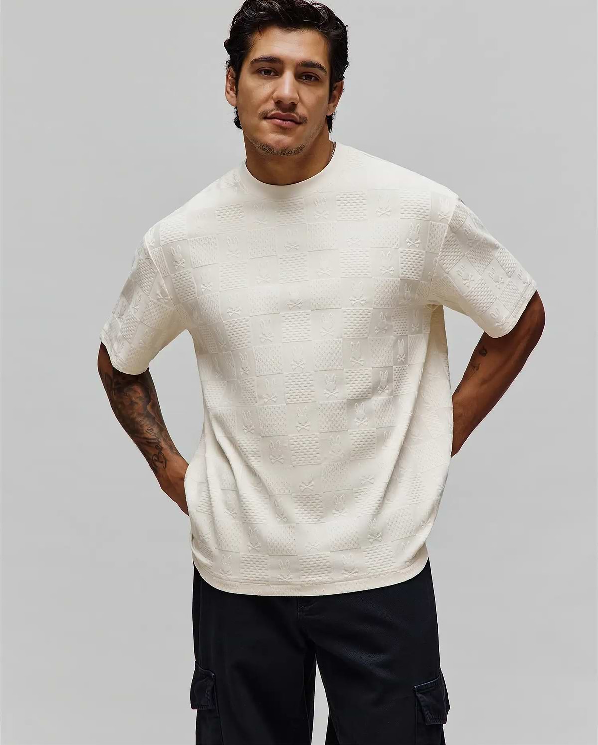 Mens Dustin Oversized Tee, cream textured knit t-shirt with an all-over embossed checkerboard pattern featuring alternating Psycho Bunny skull logos and X's.