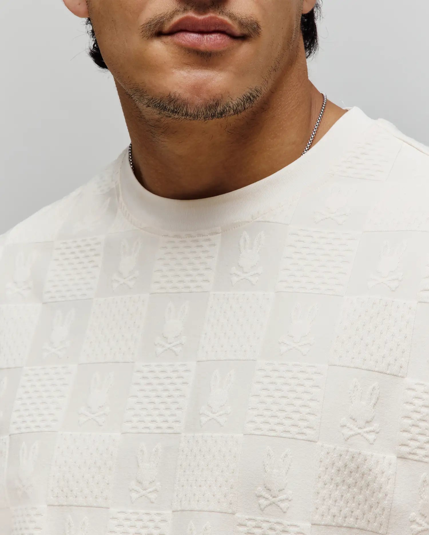 Cream Mens Dustin Oversized Tee with an all-over textured knit checkered pattern, featuring alternating squares of subtle texture and embossed Psycho Bunny skull logos.