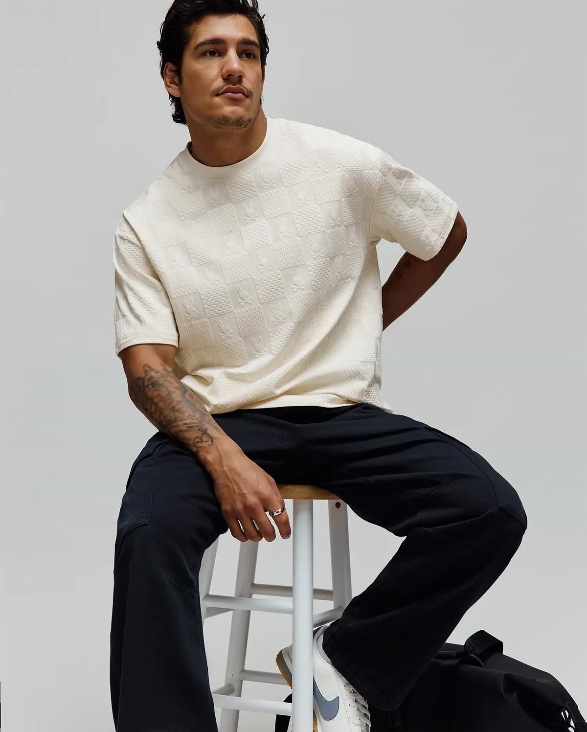 Cream Mens Dustin Oversized Tee featuring an all-over embossed checkerboard pattern with repeated small Psycho Bunny skull logos, offering a relaxed fit and textured fabric.