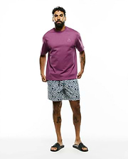 Mens Oscar Relaxed Fit Tee in plum jersey with a small embroidered Psycho Bunny skull logo on the left chest, paired with navy and white geometric pattern shorts.