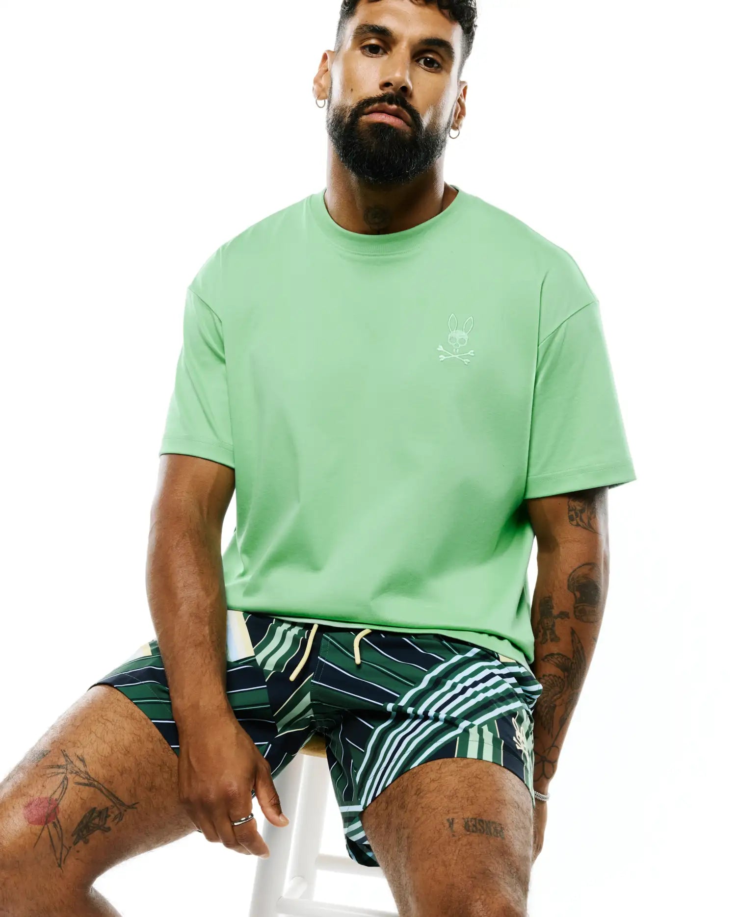 Mens Oscar Relaxed Fit Tee in light green, a smooth jersey knit with a relaxed fit, featuring a small, embroidered white Psycho Bunny skull and crossbones logo on the left chest.