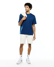 Mens Oscar Relaxed Fit Tee in deep blue jersey with a tonal embroidered Psycho Bunny skull logo on the left chest, paired with cream waffle knit shorts and white socks featuring black Psycho Bunny logos.