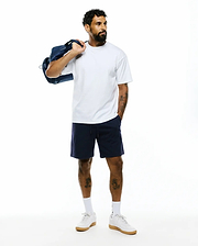 Mens Oscar Relaxed Fit Tee in white, a soft jersey crew neck with a relaxed fit. Paired with navy blue jersey shorts featuring a small white embroidered Psycho Bunny skull logo on the left leg.