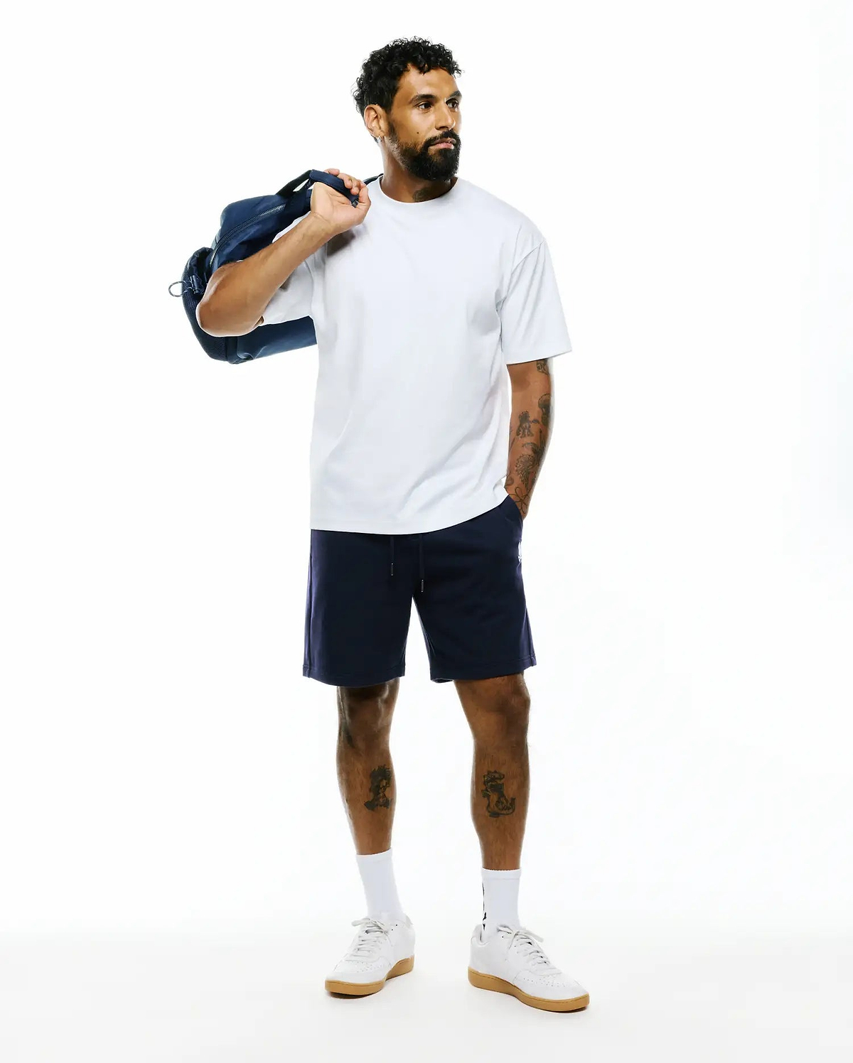 Mens Oscar Relaxed Fit Tee in white, a soft jersey crew neck with a relaxed fit. Paired with navy blue jersey shorts featuring a small white embroidered Psycho Bunny skull logo on the left leg.