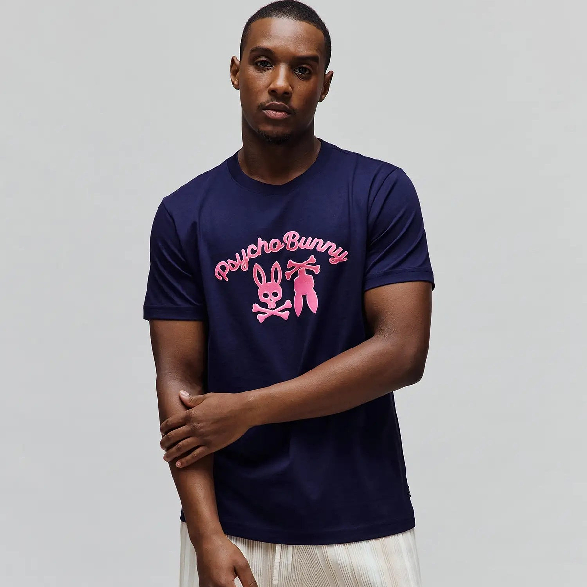Mens Aram Graphic Tee, navy blue classic fit jersey knit t-shirt with a large hot pink Psycho Bunny script and iconic bunny skull logo graphic centered on the chest.