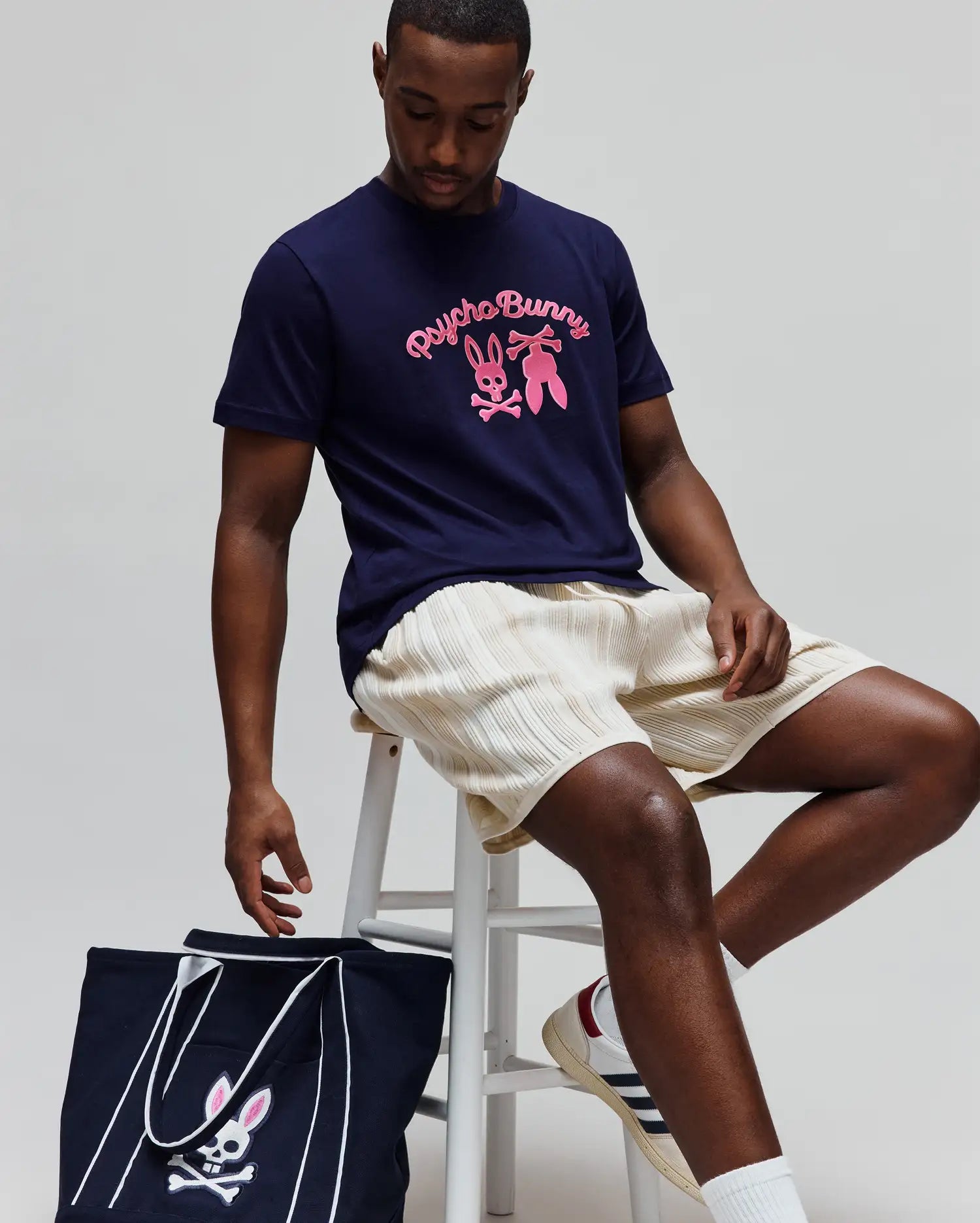 Mens Aram Graphic Tee in navy, featuring a classic fit and smooth jersey fabric. A large pink Psycho Bunny script and bunny skull graphic are prominently displayed on the center chest.