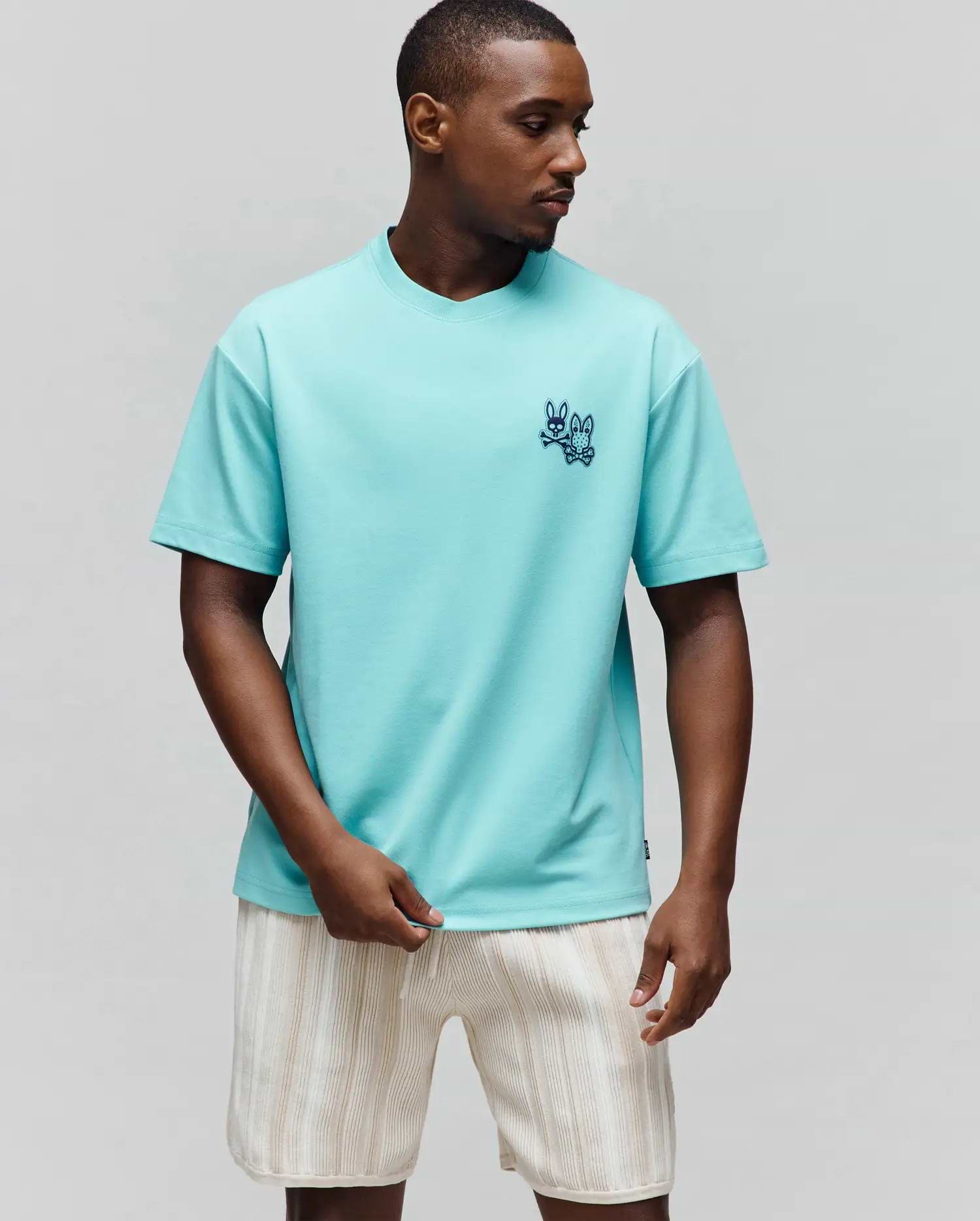 Mens Luke Back Graphic Tee in aqua jersey, featuring a relaxed fit, small embroidered dark blue Psycho Bunny skull and regular bunny logo on the left chest, and a back graphic.